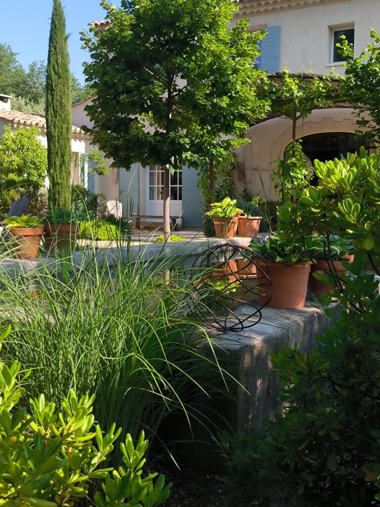 Une terrasse avec des plantes en pot devant une maison