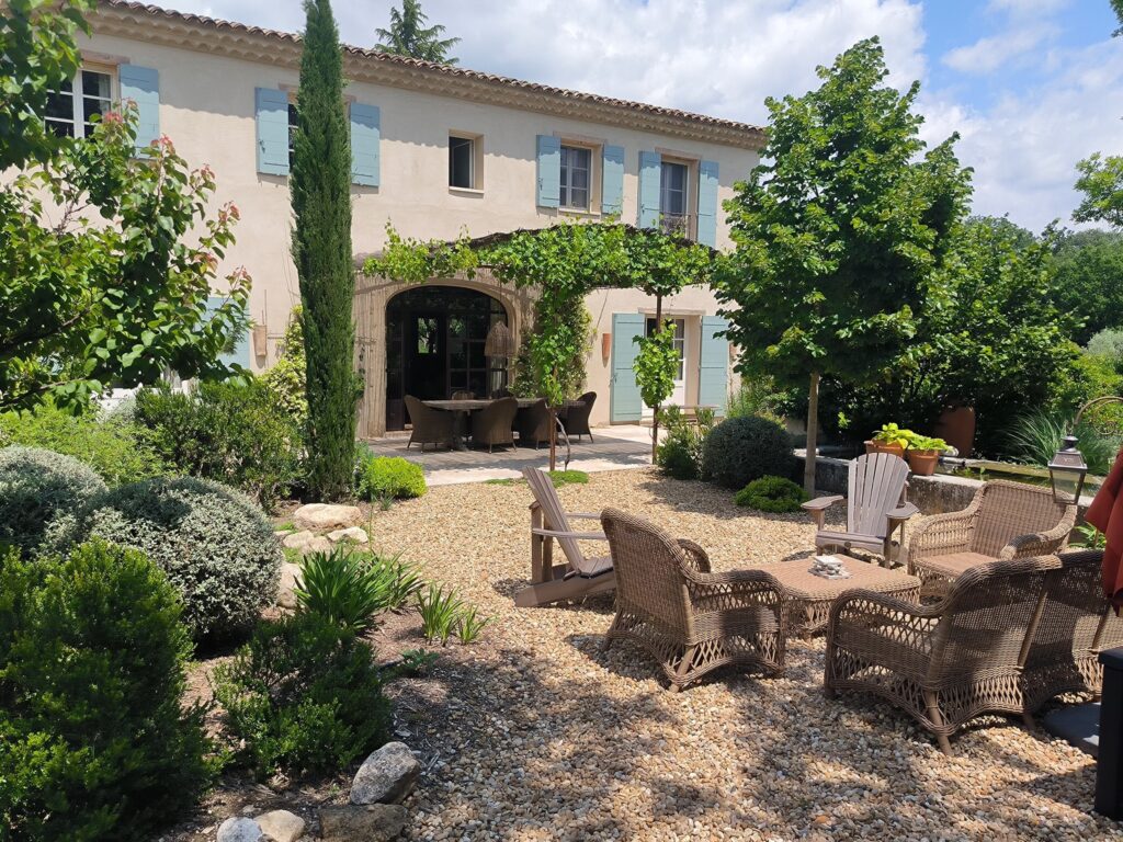 Une piscine entourée de plantes vertes dans un jardin sec.