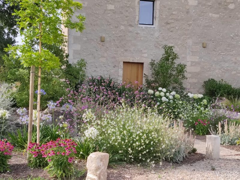 Jardin fleuri devant une maison en pierre.